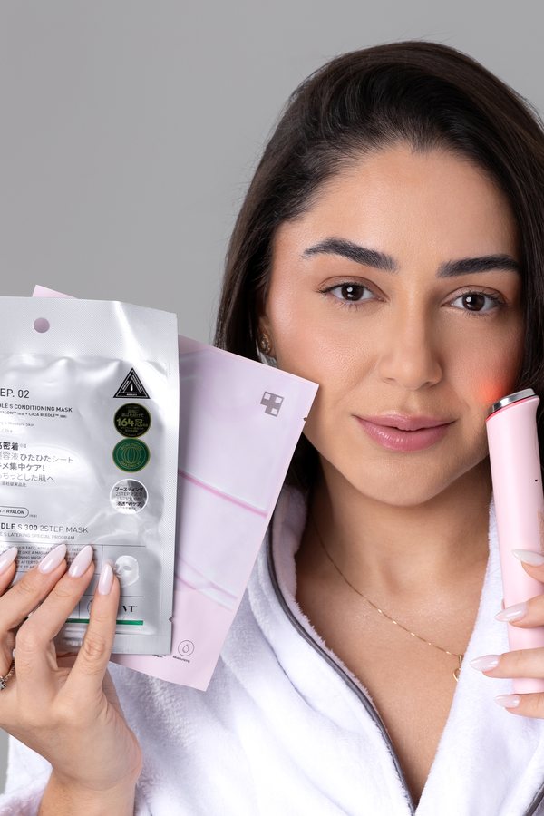 Mulher segurando sachês de máscaras faciais coreanas ao lado do rosto