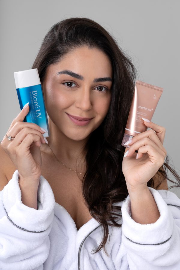 Mulher segurando dois produtos de skincare, um em cada mão, comparando as opções